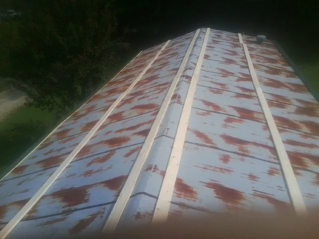 Rusted metal roof panels with new wood purlins before replacement — Storm Damage Roof Repair in Lowry by Roofing Brothers