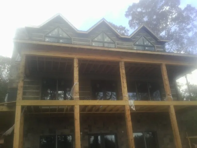 Dormers and porch framing on a large log home under construction — Roof Coating work by our crew in Lowry