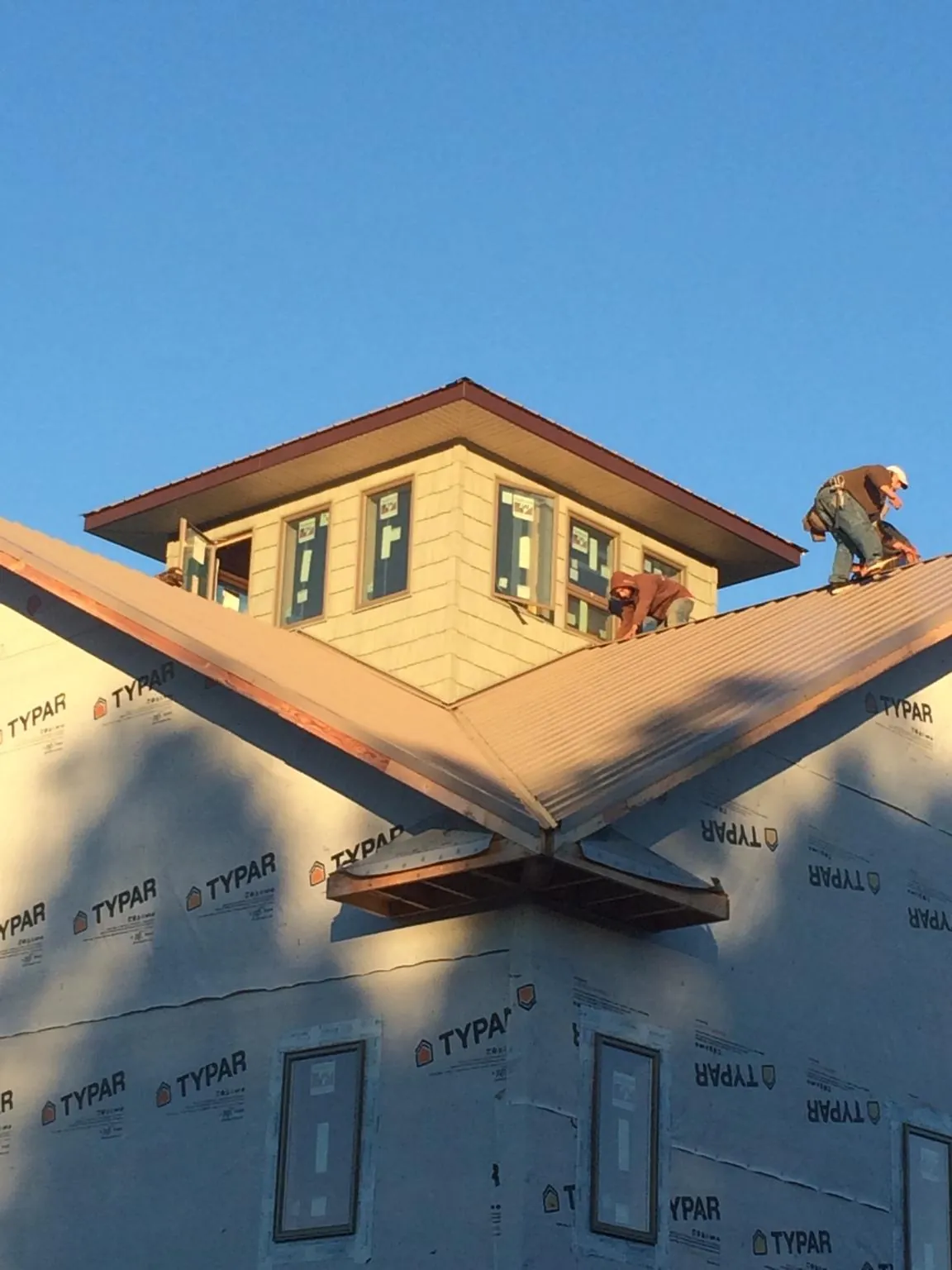 Roofers working around a rooftop cupola on a new metal roof at sunset — Roof Waterproofing in Lowry by Roofing Brothers